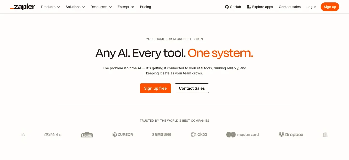Zapier AI homepage with an orange navigation bar and the centered headline “Any AI. Every tool. One system.” above sign-up buttons and a strip of company logos.