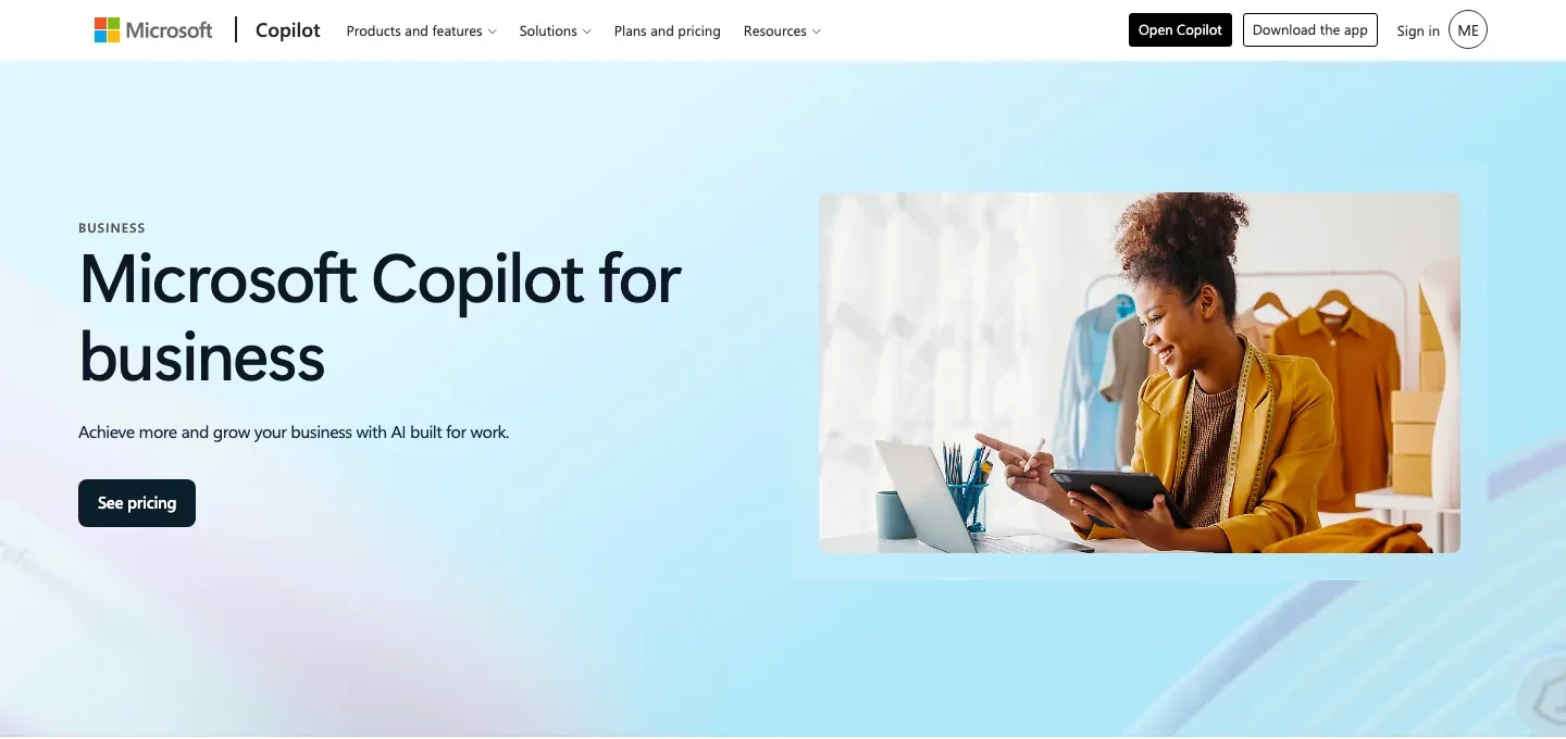 Microsoft Copilot for business homepage with a light-blue hero, business headline, and a person using a laptop and tablet, followed by Copilot overview navigation.
